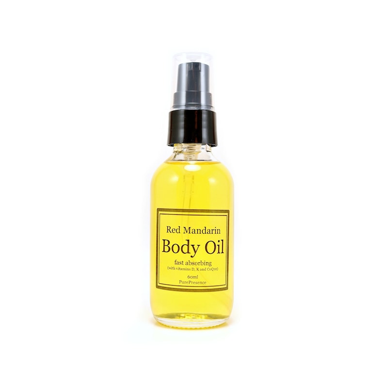 May include: A clear glass bottle of Red Mandarin Body Oil with a black pump top. The label is gold with black text that reads "Red Mandarin Body Oil fast absorbing with vitamin D, K and CoQ10 60ml Pure Presence".