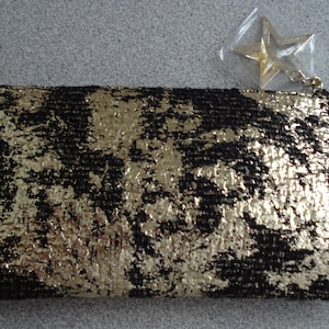 May include: A black and gold clutch purse with a star-shaped zipper pull.