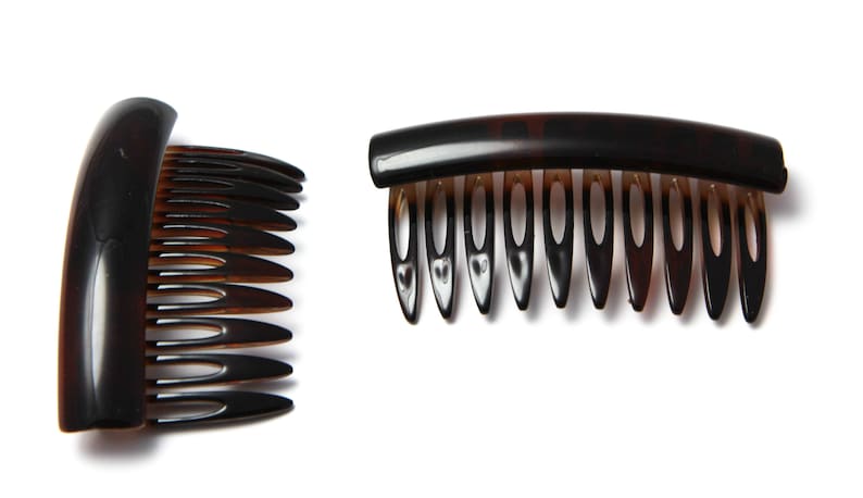 Op de afbeelding: Twee bruine plastic haar kammen. E&eacute;n kam heeft een gebogen handvat en een rij tanden. De andere kam heeft een recht handvat en een rij tanden.