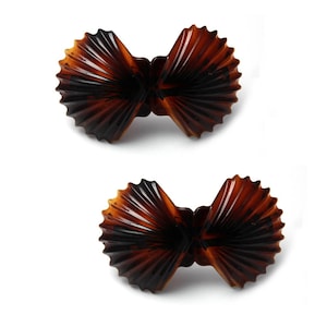 May include: Two brown plastic hair clips shaped like seashells. The clips are closed and ready to be used.