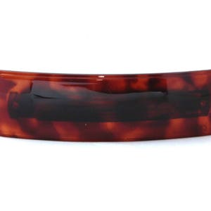 Peut inclure: Une pince à cheveux en écaille de tortue brune avec une forme incurvée.