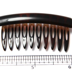 Op de afbeelding: Een bruine schildpadhaar kam met een gebogen basis en negen tanden. De kam is ongeveer 12,7 cm lang.