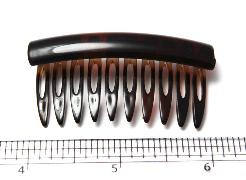 Op de afbeelding: Een bruine schildpadhaar kam met een gebogen basis en negen tanden. De kam is ongeveer 12,7 cm lang.