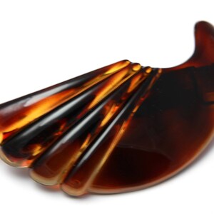 May include: A brown tortoiseshell hair clip with a fan-shaped design. The clip is made of plastic and has a smooth, glossy finish.