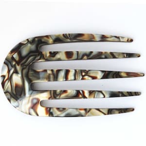 May include: A brown and white patterned hair comb with four teeth. The comb is made of plastic and has a rounded shape.