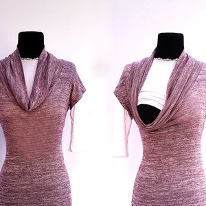 Puede incluir: Una blusa de color malva con cuello de pico y mangas cortas, con una camiseta blanca debajo. La blusa está hecha de un tejido suave y elástico y tiene un corte holgado.