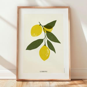 May include: A framed art print featuring a botanical illustration of lemons. The artwork showcases three bright yellow lemons on a branch with green leaves against a cream background. The word "LIMONI" is printed at the bottom of the print.