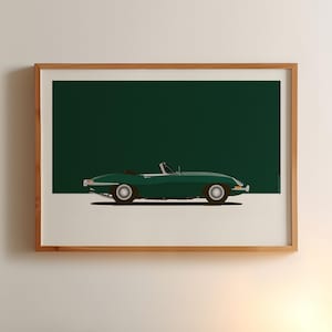 May include: A framed print featuring a green convertible car against a dark green background. The car is a classic design, with a low profile and open top. The wheels are black with silver rims, and the car is set on a white base.