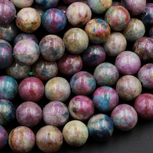 Könnte beinhalten: Eine Strähne runder, mehrfarbiger Edelsteinperlen. Die Perlen sind ein Mix aus Rosa, Blau, Grün und Braun mit einer marmorierten, gefleckten Optik.