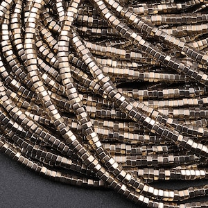 May include: A strand of gold-toned square-shaped beads. The beads are made of metal and have a shiny finish.