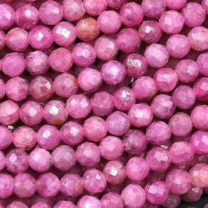 May include: A strand of pink faceted gemstone beads. The beads are round and have a smooth, polished finish.