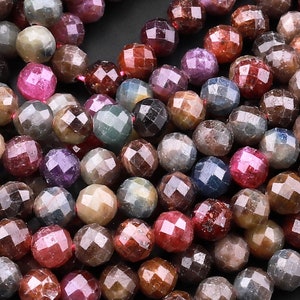 Peut inclure: Un brin de perles de pierres précieuses facettées dans des tons de rose, rouge, bleu et violet. Les perles sont toutes à peu près de la même taille et ont une surface facettées, ou taillées.