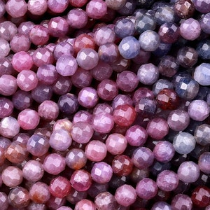 May include: A strand of faceted gemstone beads in shades of pink, purple, and blue. The beads are round and have a smooth, polished finish.