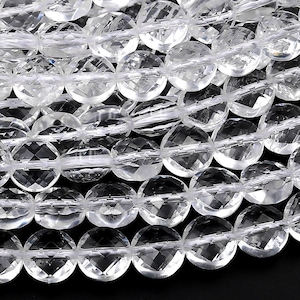 May include: Close-up of clear, faceted crystal beads strung together. The beads are round and have a sparkling, translucent appearance. The beads are on a black background.