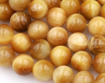Pode incluir: Um fio de contas redondas de olho de tigre marrom dourado. As contas têm um acabamento liso e polido e um brilho sutil.