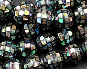 May include: A strand of round, iridescent black and green shell beads with a checkered pattern. The beads are strung on a clear cord and are approximately 1 cm in diameter.