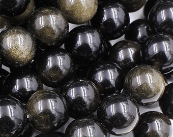 Puede incluir: Una hebra de cuentas de piedras preciosas negras y doradas. Las cuentas son redondas y tienen un acabado liso y pulido. Las motas doradas en las cuentas son visibles y añaden un toque de brillo.