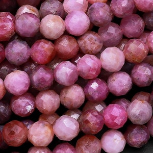 May include: A strand of pink faceted gemstone beads. The beads are round and have a smooth, polished finish.