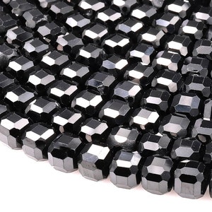 May include: A close-up of a strand of black faceted beads. The beads are arranged in a circular pattern, creating a spiral effect. The beads are shiny and reflect light.