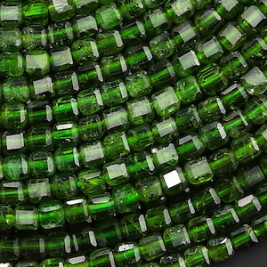 May include: A strand of green gemstone beads, each bead is a square shape with a faceted finish.