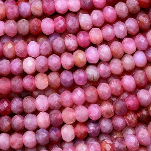 Peut inclure: Un brin de perles de rubis rose. Les perles sont facettées et ont une forme légèrement irrégulière. Elles sont enfilées sur un fil transparent.