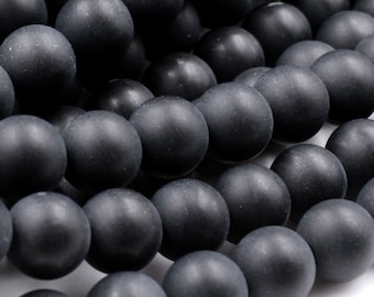 Puede incluir: Primer plano de una hebra de cuentas redondas negras mate. Las cuentas están dispuestas en un patrón escalonado, creando un aspecto texturizado.