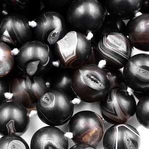 May include: A strand of black agate beads with white and brown banding. The beads are round and have a smooth, polished finish.