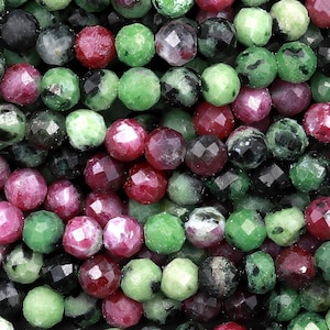 Puede incluir: Una hebra de cuentas de piedras preciosas facetadas verdes y rojas. Las cuentas son redondas y tienen un acabado pulido.