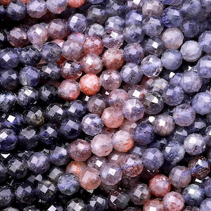 May include: A strand of faceted gemstone beads in shades of blue, purple, and pink. The beads are round and have a slightly irregular shape.
