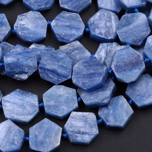 Puede incluir: Una hebra de cuentas de piedra preciosa de cianita azul, cada cuenta está facetada y tiene una forma hexagonal. Las cuentas están enhebradas en un cordón azul.
