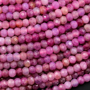 Könnte beinhalten: Eine Strähne rosafarbener facettierter Edelsteinperlen. Die Perlen sind klein und rund, mit einer glatten, polierten Oberfläche.