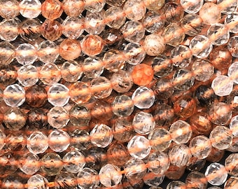 May include: A strand of faceted, translucent, light brown and clear quartz beads with inclusions. The beads are approximately 6mm in diameter.
