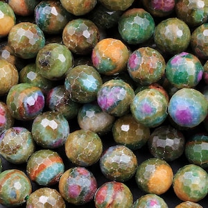 Peut inclure: Un brin de perles de pierres précieuses facettées vertes, roses et brunes. Les perles sont rondes et ont une surface texturée.