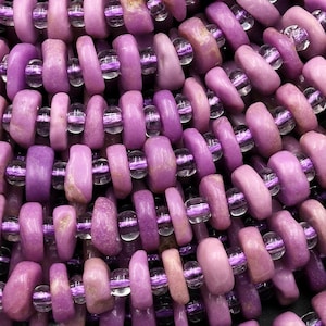 May include: A strand of purple and clear gemstone beads. The beads are round and have a smooth, polished finish. The beads are strung on a clear thread.
