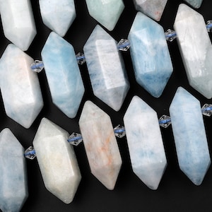 May include: A strand of light blue aquamarine gemstone beads, each bead is faceted and shaped like a long, narrow, hexagonal prism. The beads are strung on a clear thread and are arranged in a staggered pattern.