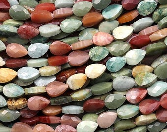 May include: A close-up shot of a collection of teardrop-shaped gemstone beads in various colours, including red, green, orange, and pink. The beads are arranged closely together, creating a textured surface. Suitable for jewellery making.