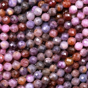 May include: A strand of faceted gemstone beads in shades of pink, purple, and blue. The beads are round and have a smooth, polished finish.