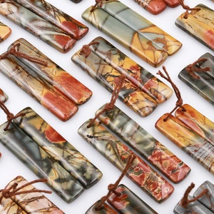 May include: A collection of 20 pairs of rectangular, natural stone earrings. Each pair is made of two pieces of stone with a brown, red, and gray marbled pattern. The stones are tied together with brown string.
