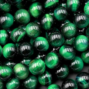 May include: A close-up of a strand of green tiger's eye beads. The beads are round and smooth, with a subtle shimmer.