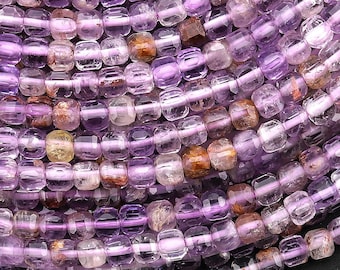 May include: A strand of purple amethyst beads, each bead is faceted and has a square shape. The beads are translucent and have a slight shimmer.
