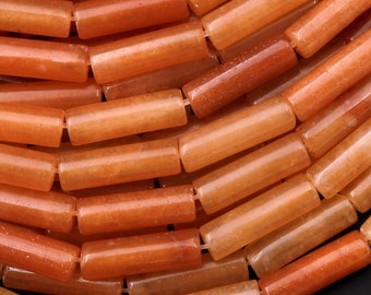May include: A strand of orange and brown gemstone beads, each bead is a smooth, polished cylinder.