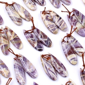 May include: A collection of 24 purple and white striped gemstone pendants with brown leather cords. The pendants are shaped like teardrops and have a natural, polished finish.