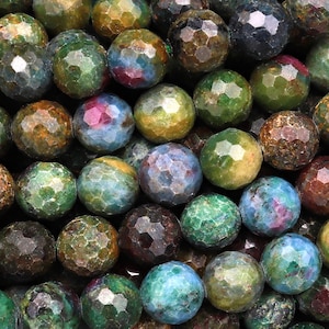 Pode incluir: Um close-up de um fio de contas de pedras preciosas facetadas. As contas são uma mistura de cores verde, azul e marrom com um padrão salpicado.