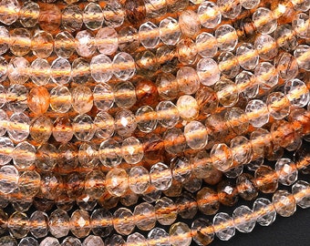 May include: A strand of faceted, translucent, golden rutilated quartz beads. The beads are round and have a natural, irregular shape. The beads are strung on a clear elastic cord.