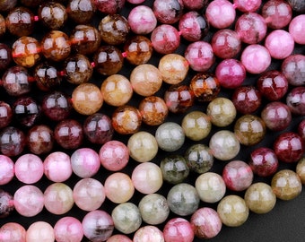 Peut inclure: Un brin de perles rondes en pierres précieuses multicolores. Les perles sont un mélange de rose, brun, vert et noir. Les perles sont toutes à peu près de la même taille et sont enfilées sur un fil transparent.