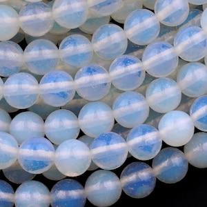 May include: A strand of white opal beads with a blue iridescent sheen. The beads are round and smooth, and they are strung on a clear thread.