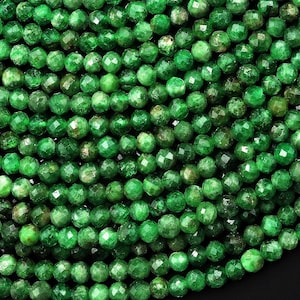 May include: A strand of green emerald faceted beads. The beads are round and have a smooth, polished finish.
