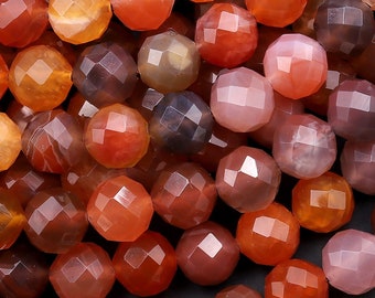 May include: A close-up of a strand of faceted carnelian beads. The beads are a mix of orange, red, and brown colors. The beads are all faceted and have a shiny finish.