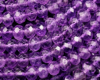 May include: A strand of faceted amethyst beads, each bead is a deep purple color and has a faceted, round shape.