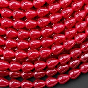 May include: A strand of bright red teardrop-shaped beads. The beads are made of glass and have a smooth, glossy finish.